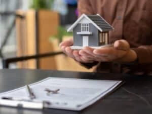 un modellino di una casa nelle mani di una persona, simbolo di proprietà