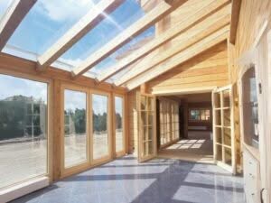 Ampia veranda in legno con grandi vetrate in una casa in XLAM, luminosa e spaziosa