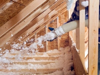 Applicazione di isolamento termico mediante insufflaggio in una soffitta.