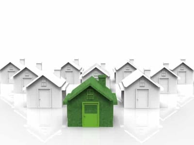 una casa verde (simbolo di passivhaus) che si distingue in un gruppo di case bianche